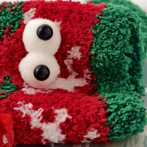 Close-up of fluffy coral fleece Christmas socks with cute cartoon 3D eyes and soft texture