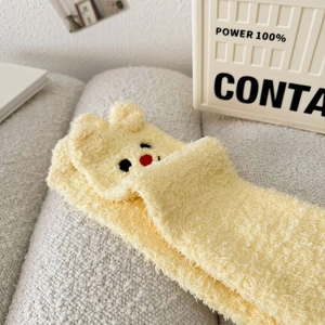 Detail von gelben Korallenvlies-Socken mit 3D-Ohren und Bärenstickerei für den Winter