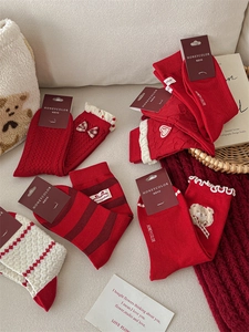Detail of red festive mid-calf socks with bows, heart embroidery and teddy bear charms