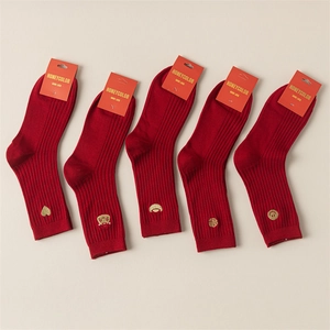 Detail of five pairs of red festive socks with golden embroidery and rib knit texture