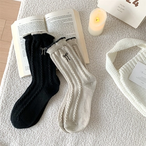 Detail of wool socks showing ribbed texture, bow embroidery and lettuce edge cuffs