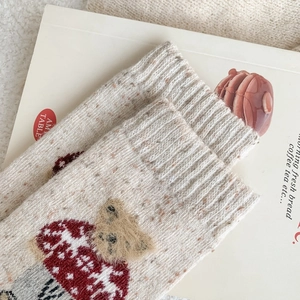 Detail of beige knit socks featuring cute 3D plush bear head and red mushroom jacquard