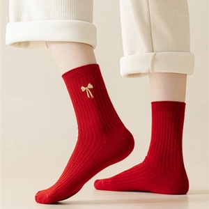 Detail of red cotton festive socks with gold bow embroidery and vertical ribbed texture