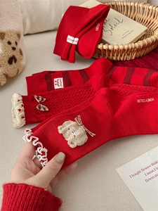 Detailed close-up of festive red knit socks with white lace trim and plaid bow accents
