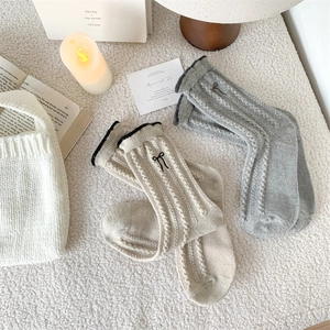 Detailed knit texture of wool socks featuring cute black bow embroidery and ribbed cuffs