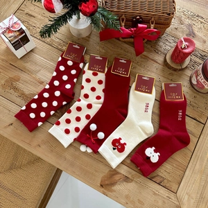Close-up of five pairs of red and white Christmas socks with holiday motifs on wood