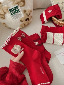 Close-up of red cotton holiday socks featuring a 3D bear motif and festive bow details