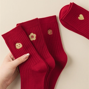 Detailed view of red cotton socks featuring gold zodiac embroidery and ribbed texture