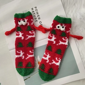 Christmas coral fleece socks with 3D eyes and tiny hands on white plush background