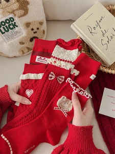 Detailed view of red cotton socks with lace trim, bows, and festive embroidery details