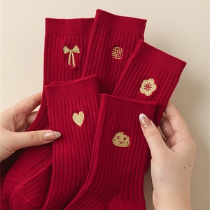 Detail of red festive cotton socks featuring golden embroidery and classic ribbed texture