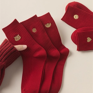 Detail of red festive socks with gold embroidery showing elastic ribbed cuffs and cotton texture