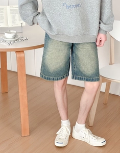 Detail of light blue denim shorts featuring double-stitched hem and vintage wash texture