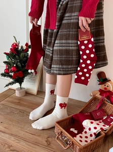 Close-up of festive red Christmas socks with pom-poms and hearts in a gift box
