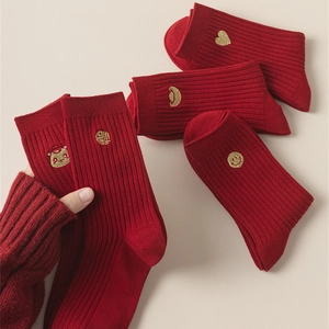 Detailed close-up of dark red ribbed knit socks featuring delicate gold embroidery icons