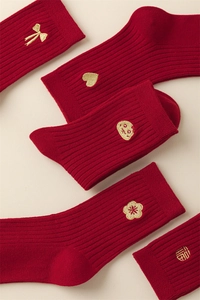 Detail of red festive cotton socks with vertical knit and gold zodiac embroidery patterns