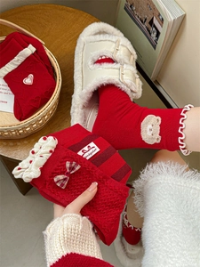 Detail of red festive cotton socks with bow and bear embroidery in cozy home setting