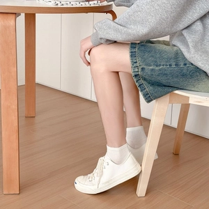 White low-top canvas sneakers paired with cotton socks in a clean home setting