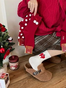 Close-up of festive red and white rabbit wool socks set with pompom and cherry details
