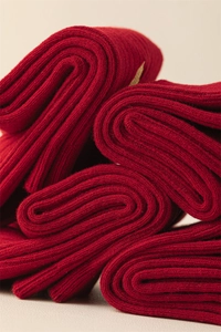 Macro shot of thick red knitted cotton socks with vertical ribbed texture and soft fabric