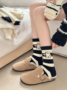 Close-up of warm striped cartoon socks with plush slippers in a cozy bedroom setting
