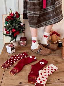 Detailed view of red Christmas cotton socks with heart embroidery and fluffy pom-pom balls