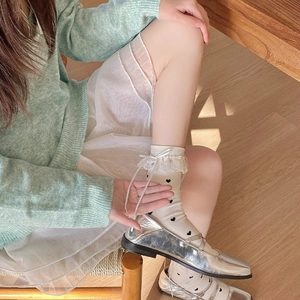 Detail of cream lolita socks with lace trim, white bows, and black heart pattern