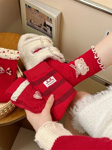 Detail of red festive socks featuring bow accents, heart textures, and delicate ruffled edges