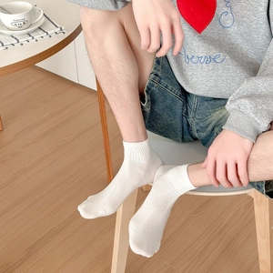 Men's white mesh low-cut sports socks with ribbed cuffs on wooden floor background