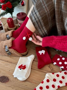 Close-up of red festive knit socks with white pom-poms and cherry embroidery details