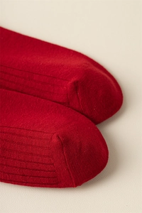 Detailed close-up of red ribbed knit texture and smooth toe stitching of the cotton socks