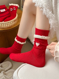 Detail of red mid-calf socks with white ruffled cuffs and heart embroidery for women