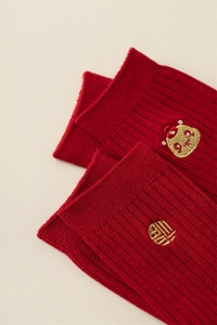 Detail of red festive socks with golden fortune embroidery and traditional lion dance pattern