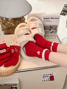 Detail of red cotton socks with heart embroidery paired with white plush slippers