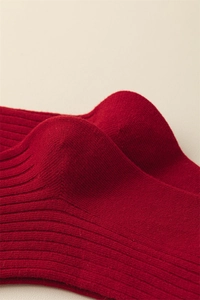 Macro detail of reinforced heel on red cotton socks with fine ribbed knit texture