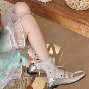 Close-up of lolita style crew socks with black heart patterns and lace ribbon details