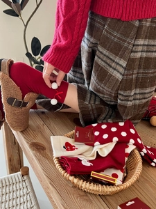 Detail of red festive rabbit wool socks with white pom-poms and cute heart patterns