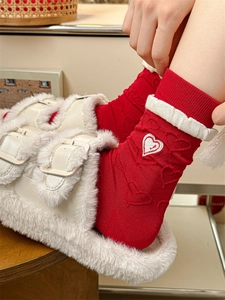 Detail of red knitted socks with heart embroidery and plush faux fur slippers