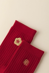 Close-up of red ribbed socks with golden Fu character and plum blossom embroidery