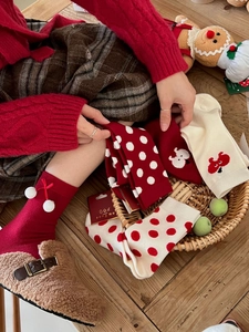 Close-up of festive red Christmas socks with cute white polka dots and soft pom-pom details