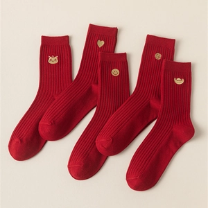 Close-up of five pairs of red cotton socks with gold embroidery of lucky symbols and hearts