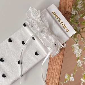 Detail of white Lolita socks with black heart patterns and delicate lace ribbon bows
