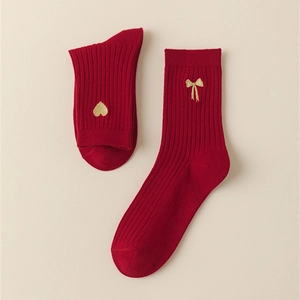 Detail of red ribbed cotton socks with gold heart and bow embroidery for festive wear