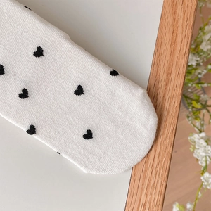 Close-up of white Lolita socks featuring black heart patterns and delicate knit texture