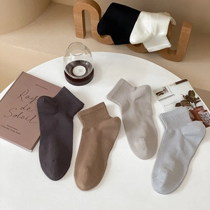 Detailed close-up of earth-toned cotton socks with ribbed cuffs on a minimalist wooden table