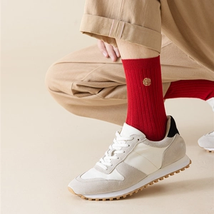 Detail of red crew socks with gold Fu embroidery paired with white sneakers