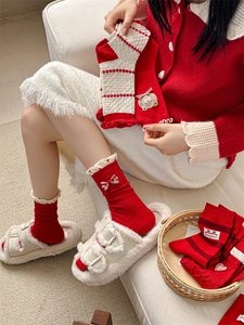 Close-up of red and white knit socks with bows and bear patches for winter