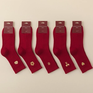 Detail of red cotton socks featuring golden embroidery patterns and ribbed cuffs texture