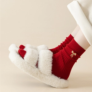 Detailed embroidery of a golden bow on festive red cotton socks with plush slippers