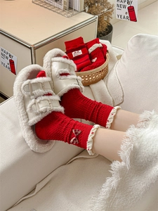Detail of red festive socks with plaid bow, heart embroidery and ruffled cuff design
